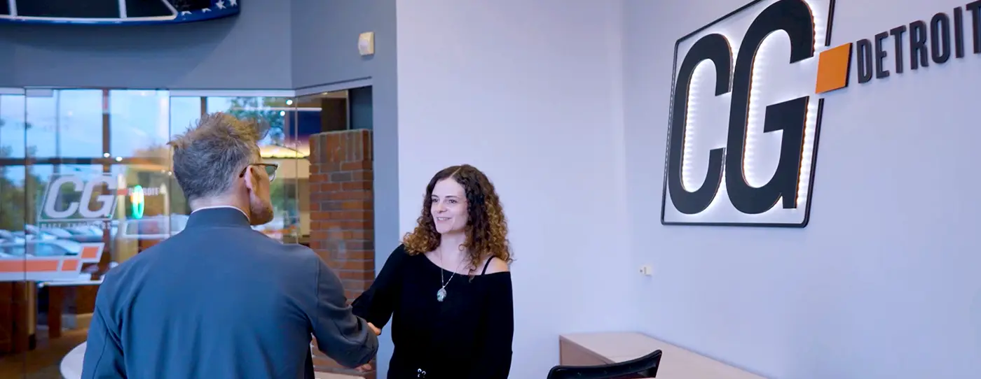 A CG account representative shakes hands with a customer in the CG lobby.