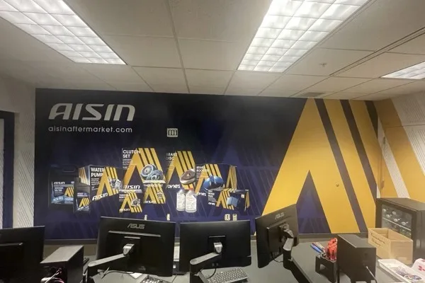 Gold angular wall graphics behind the AISIN wordmark in a reception area