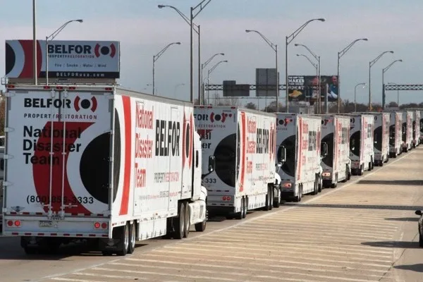 A BELFOR National Disaster Team convoy lined up on a highway, every trailer carrying the same livery