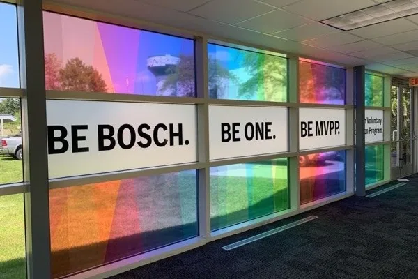 Backlit color panels reading Be Bosch, Be One, Be More along a corridor