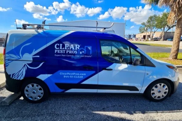 A CLEAR Pest Pros service van in full livery, with a roof rack and ladder