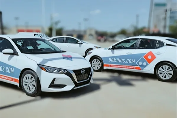Domino's delivery cars in a row, each carrying the same door and rear branding