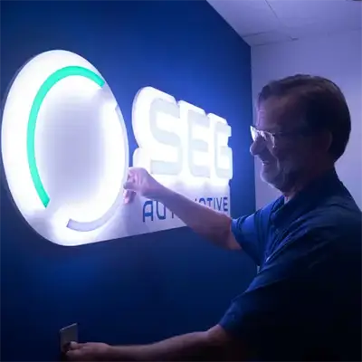 An expert installing a custom interior brand sign, that is illuminated from within and controlled by a light switch on the wall.
